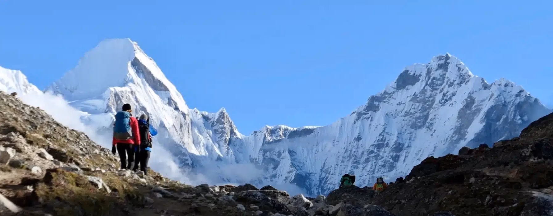 Trekkers walking towards the snow-capped Everest Base Camp peaks.